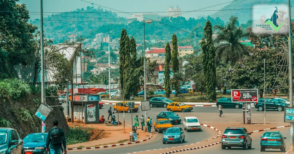Taxis and cars circle a roundabout in Yaoundé, with hillside neighbourhoods behind.